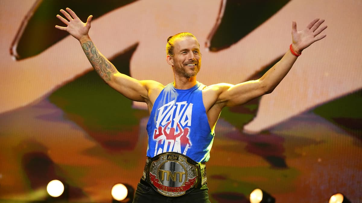 Adam Cole opposing in a blue vest and TNT Championship around his waist