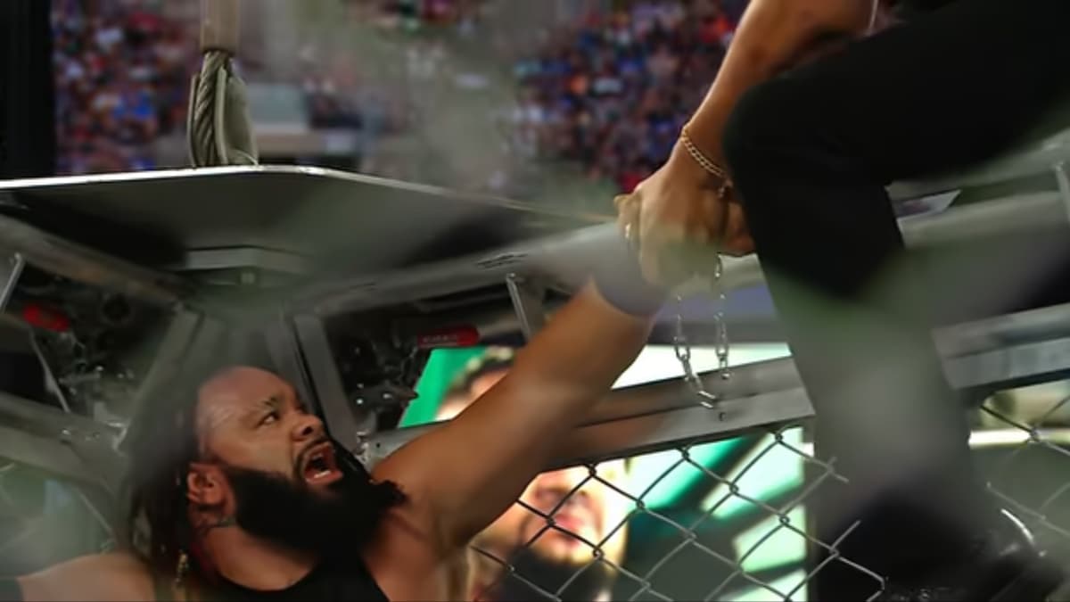 Jacob Fatu with his arm handcuffed to the cage looking despondent 