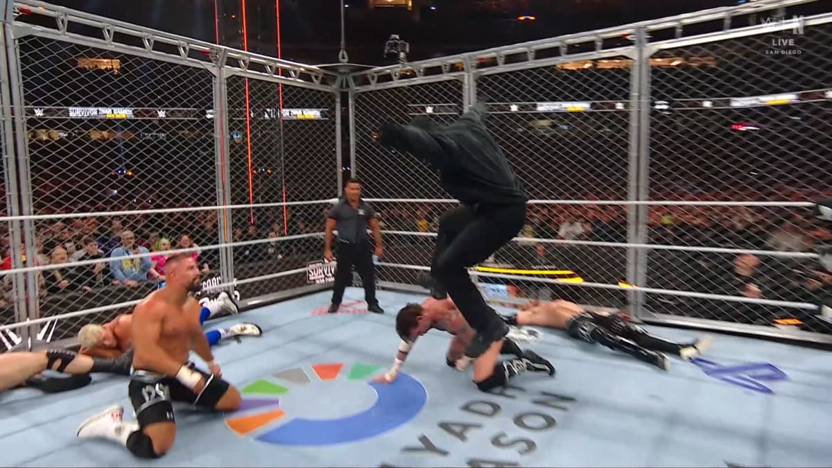 Austin Theory (dressed all in black) hitting a stomp to CM Punk at Survivor Series