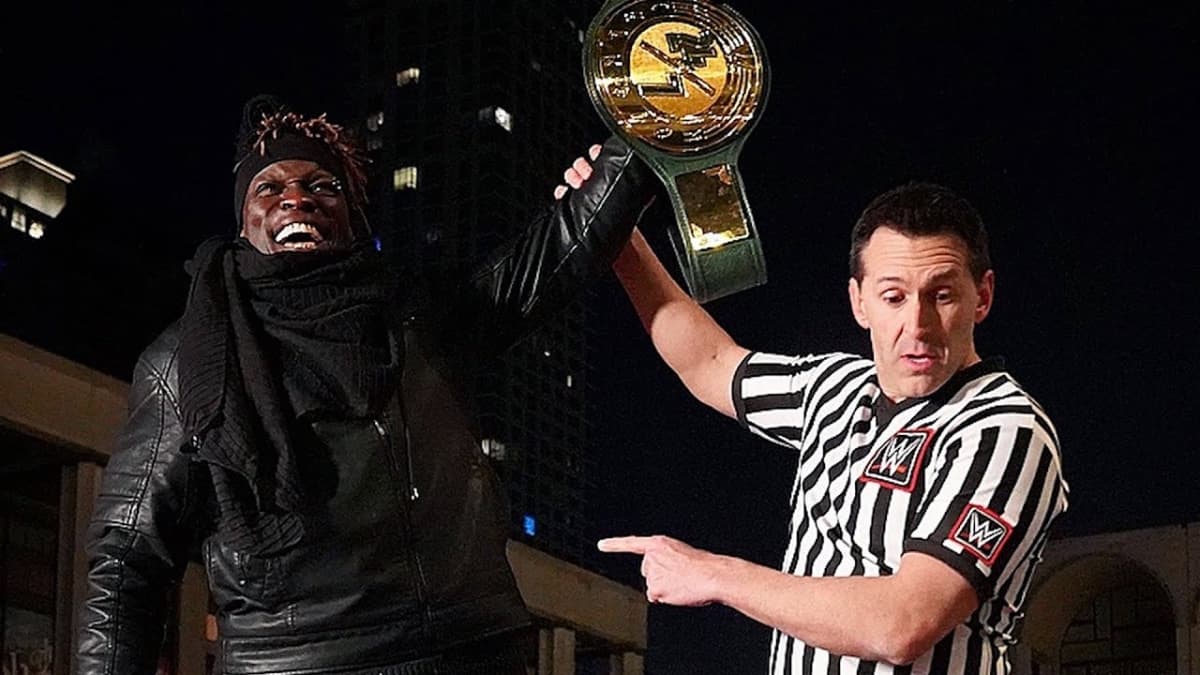 R-Truth with his hand raised holding the 24/7 Title 