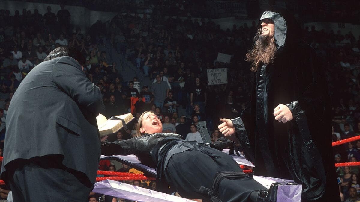 Stephanie McMahon tied to a cross on WWE Raw with the hooded Undertaker looking on 