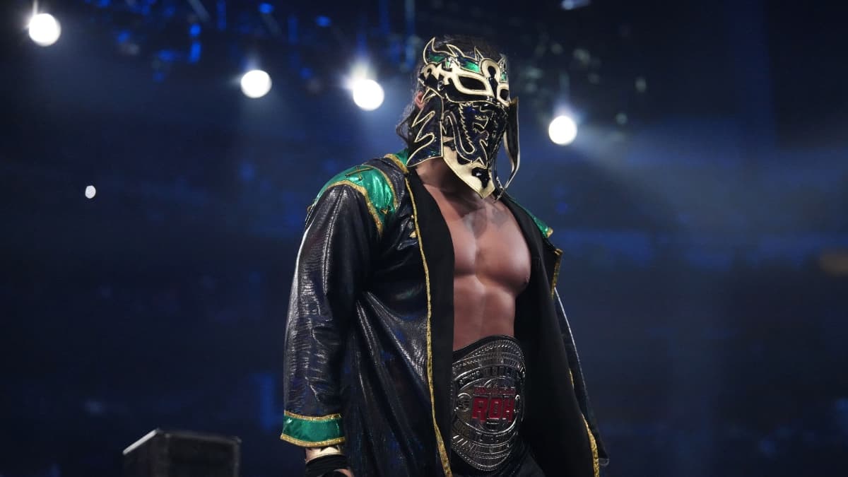 Bandido wearing a mask and green and black coat with the ROH World Title around his waist