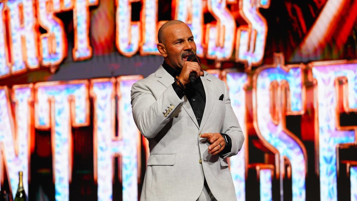 Chavo Guerrero in a grey suit and holding a microphone on TNA IMPACT