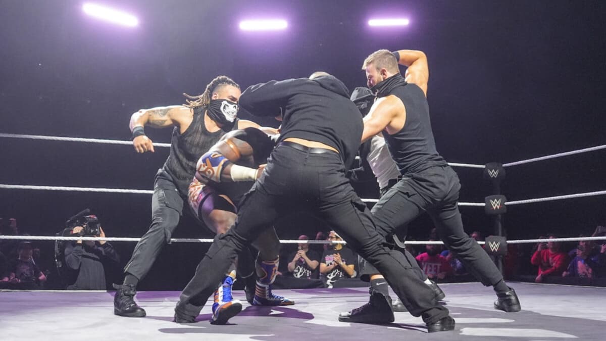 Four men beating down Oba Femi in an NXT ring